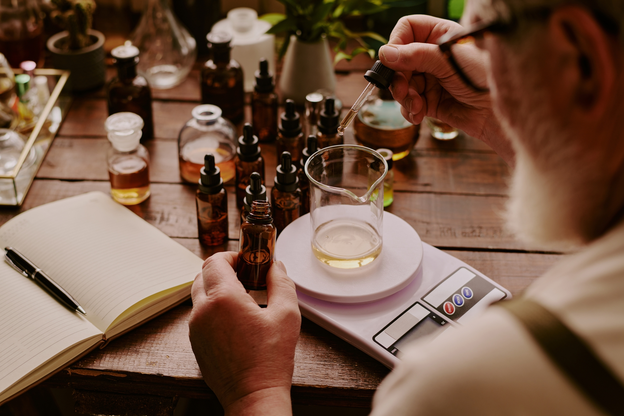 Over,Shoulder,Shot,Of,Mature,Perfumer,Adding,Extra,Essential,Oil